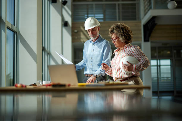 Two architects reviewing blueprints at a construction site